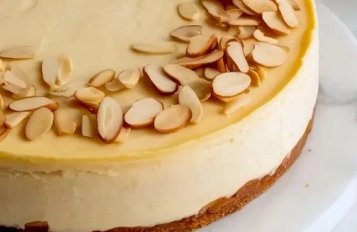 Slice of Almond Amaretto Cheesecake topped with almonds and a drizzle of amaretto