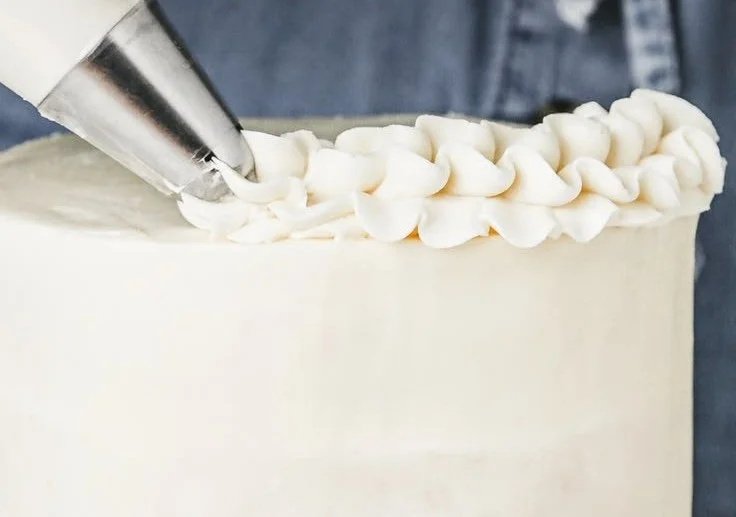 A bowl of creamy American buttercream frosting ready for decorating cakes.