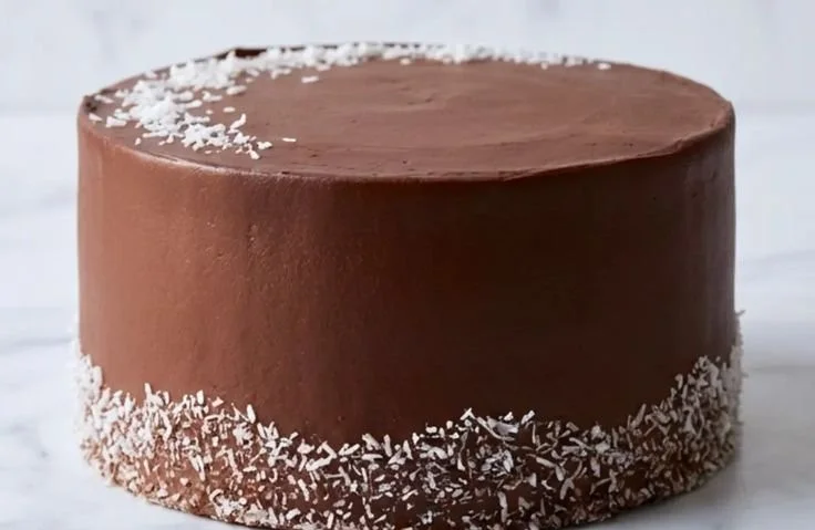 Delicious chocolate coconut cake topped with coconut flakes and chocolate frosting.