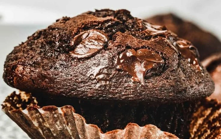 Double chocolate chip muffins fresh out of the oven, topped with chocolate chips.