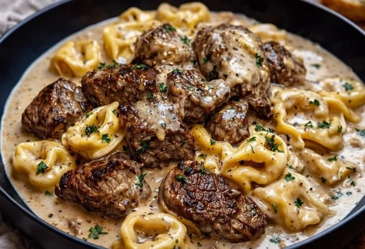 Delicious plate of garlic steak pasta garnished with herbs.