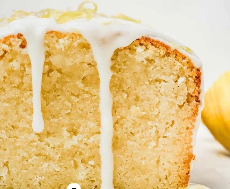 Slice of easy lemon cake with lemon zest and frosting on a plate