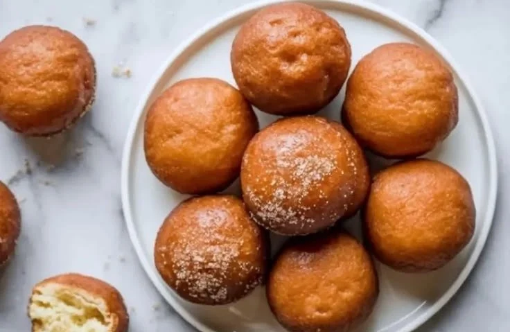 A platter of homemade gluten free donut holes dusted with powdered sugar.