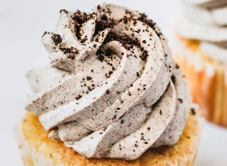 Oreo whipped cream frosting piped on a chocolate cupcake