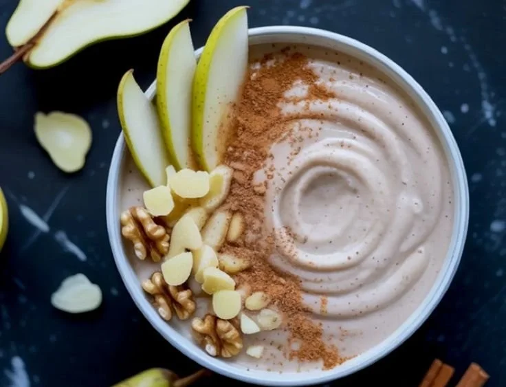 Delicious pear ginger smoothie bowl topped with fresh fruits and seeds.