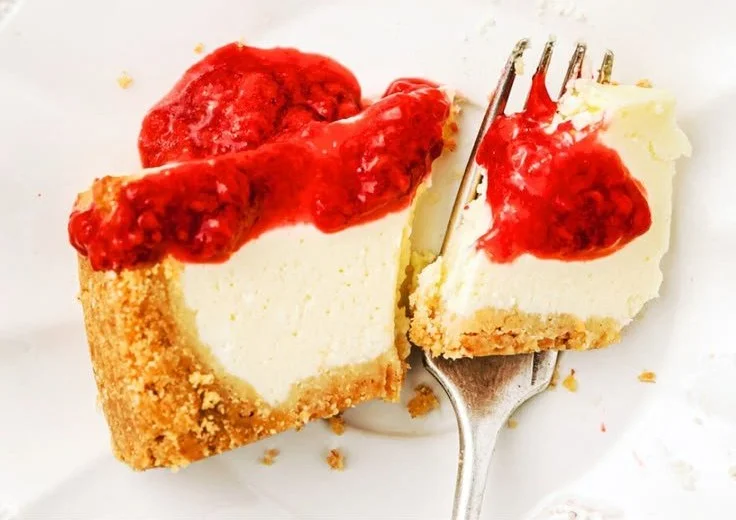 Delicious raspberry sauce drizzled over a slice of cheesecake