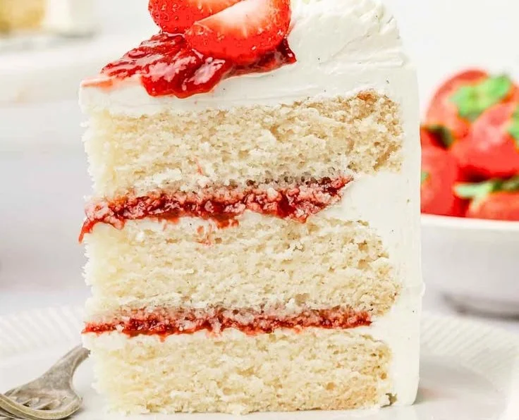 Deliciously frosted Strawberry Vanilla Cake with fresh strawberries on top