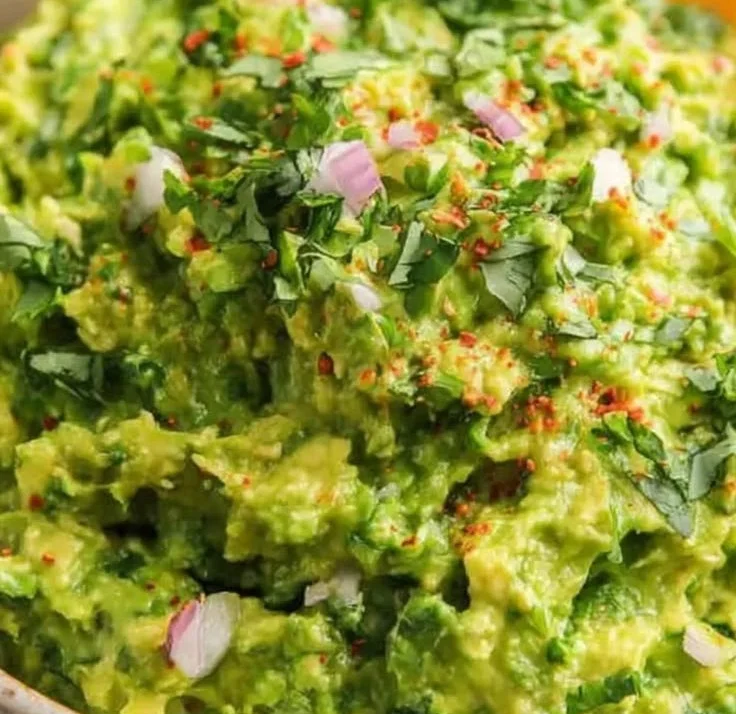 Bowl of authentic guacamole made with fresh avocados, tomatoes, and cilantro