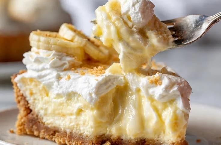A delicious slice of banana pudding cheesecake topped with whipped cream and banana slices.