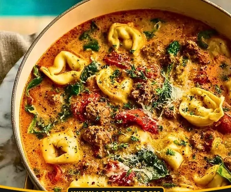 Bowl of creamy tomato tortellini soup garnished with herbs and cheese