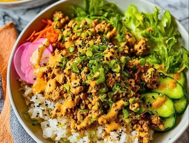Healthy ground turkey rice bowls topped with fresh vegetables and herbs