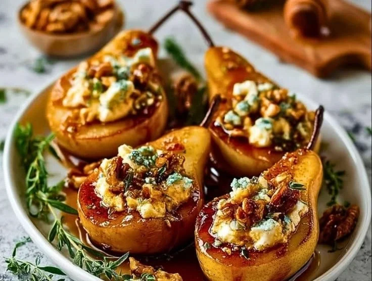 Roasted pears topped with goat cheese and maple walnut drizzle on a white plate