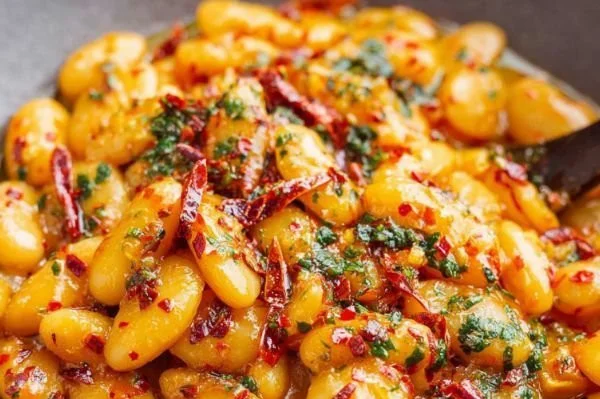Plate of butter beans in smoky tomato sauce with fresh herbs