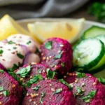 Deliciously vibrant beet falafel served with fresh greens and dipping sauce.