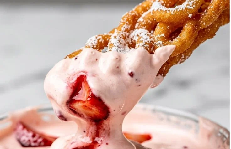 Delicious funnel cake fries with strawberry cheesecake dip served in a bowl.