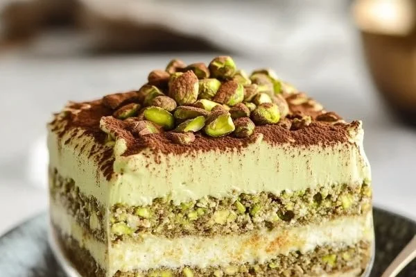 Delicious pistachio tiramisu dessert served in a glass with a sprinkle of nuts.